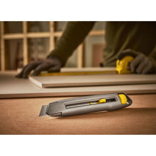 STANLEY 0-10-018 utility knife with retractable blade on worktable, construction scene.
