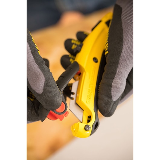 Photo of STANLEY 0-10-778 utility knife in yellow and black being used with gloved hands.