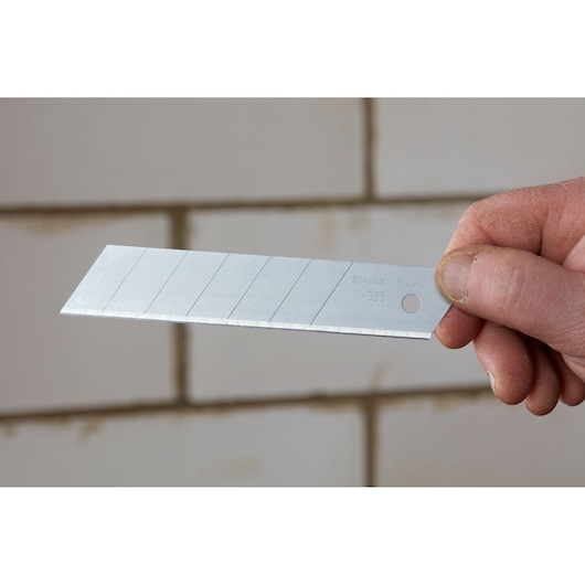 Photo of STANLEY 0-11-325 snap-off utility knife blade held by hand, silver color, multiple snap lines visible.