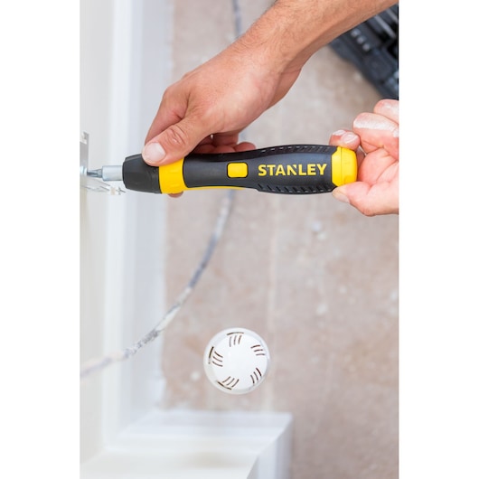 Photography of STANLEY 0-63-038 screwdriver with yellow and black handle in use near a wall.