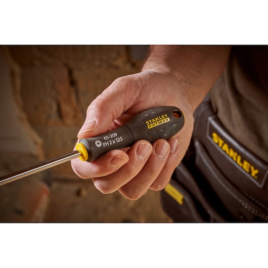 Photo of STANLEY 0-65-209 screwdriver with black and yellow handle, held in hand, close-up view.