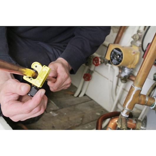STANLEY 0-70-447 pipe cutter in use cutting copper pipe in plumbing setting.