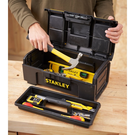 STANLEY 1-79-216 tool box with yellow tools including hammer and level, open on a workbench, front angle.
