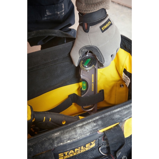 Photo of STANLEY 1-93-950 tool bag with worker placing digital angle gauge inside, close-up top view.