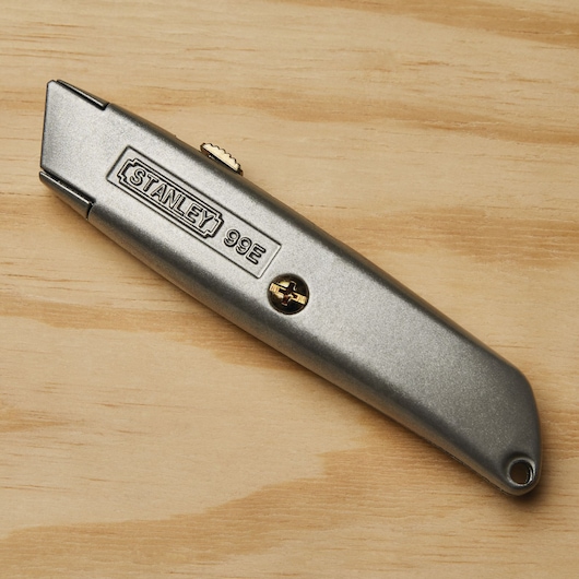 STANLEY 10-099 utility knife with silver metal body, photographed on wood surface.