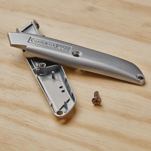 STANLEY 10-099 utility knife casing and screw on wooden surface, photography of tool parts.