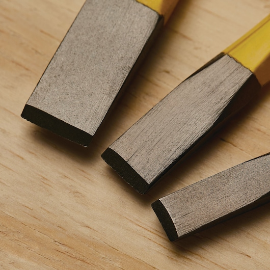 Stanley 16-299 chisel set close-up on wood surface, showing metal blades and yellow handles.