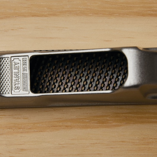 Stanley 21-399 metal rasp tool close-up on a wooden surface, showing textured handle and grating.