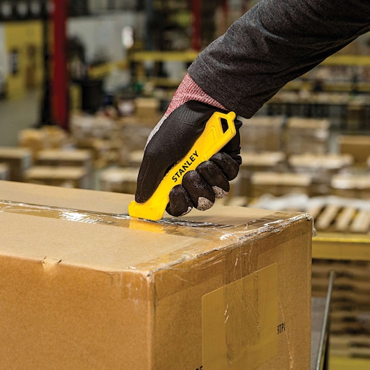 Single Sided Pull Cutter being used for cutting cello tape on cardboard box.