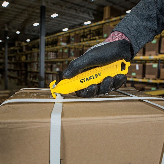 Double Sided Pull Cutter being used for cutting plastic packing rope on cardboard box.