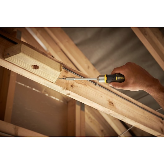 STANLEY FMHT0-62691 screwdriver used on wood beam, side angle, photo of product in construction setting.
