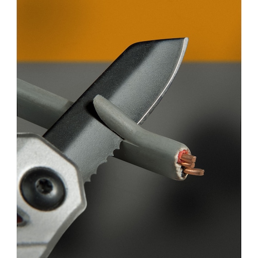 STANLEY FMHT0-72414 serrated blade cutting a grey electrical wire, close-up view.