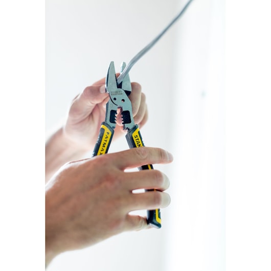 STANLEY FMHT0-75469 FATMAX pliers with yellow and black handles strip electrical wire in hand.