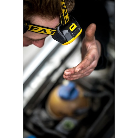 STANLEY FMHT81509-0 headlamp on person working with dirty hand near machinery, close-up photography.