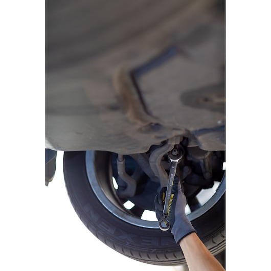 Photo of STANLEY FMMT13084-0 wrench used on car suspension by gloved hand, automotive context.