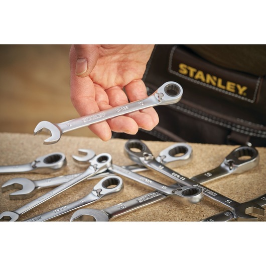 Photo of STANLEY FMMT13096-0 ratcheting wrench set, hand holding one wrench, wrenches on a work surface.