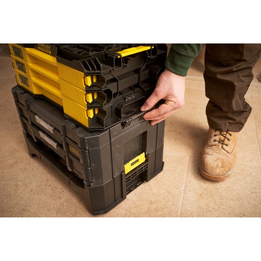 STANLEY FMMT98107-1 stackable toolboxes with yellow and black design, shown being latched together on tile floor.