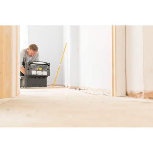 STANLEY FMST1-75792 tool box in use in a hallway, black case with yellow branding, person in background.