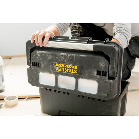 Photo of STANLEY FMST1-75792 black toolbox with transparent compartments being handled in a workspace.
