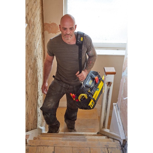 Photo of STANLEY FMST83297-1 tool bag with shoulder strap and tools, carried by person up stairs.