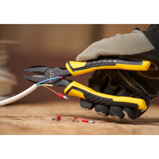 STANLEY STHT0-74456 diagonally angled pliers with yellow and black grip cutting electrical wire.