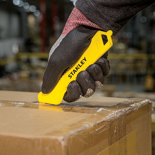 STANLEY STHT10355 yellow safety knife cutting box tape, warehouse setting, closeup photography.