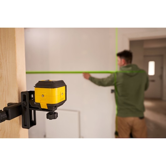 STANLEY STHT77499 photography of yellow laser level mounted on wood, projecting green lines on wall.