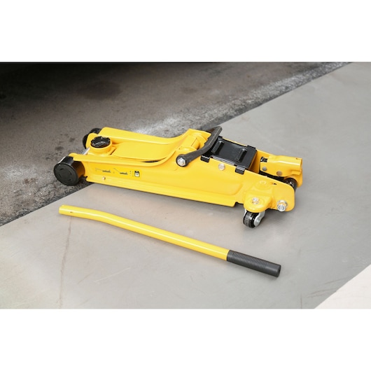 STANLEY STMT81251-1 yellow hydraulic floor jack with handle, side angle, on concrete surface.