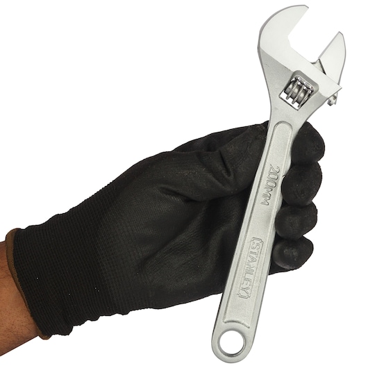Stanley STMT87432-8 adjustable wrench held by gloved hand, side view, silver finish, tool category.