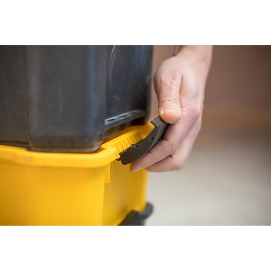 STANLEY STST1-80151 photography of tool used to open yellow storage box lid close-up.