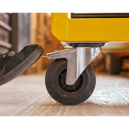 Photo of STANLEY STST74305-1 caster wheel with brake, attached to yellow tool chest, close-up side angle.